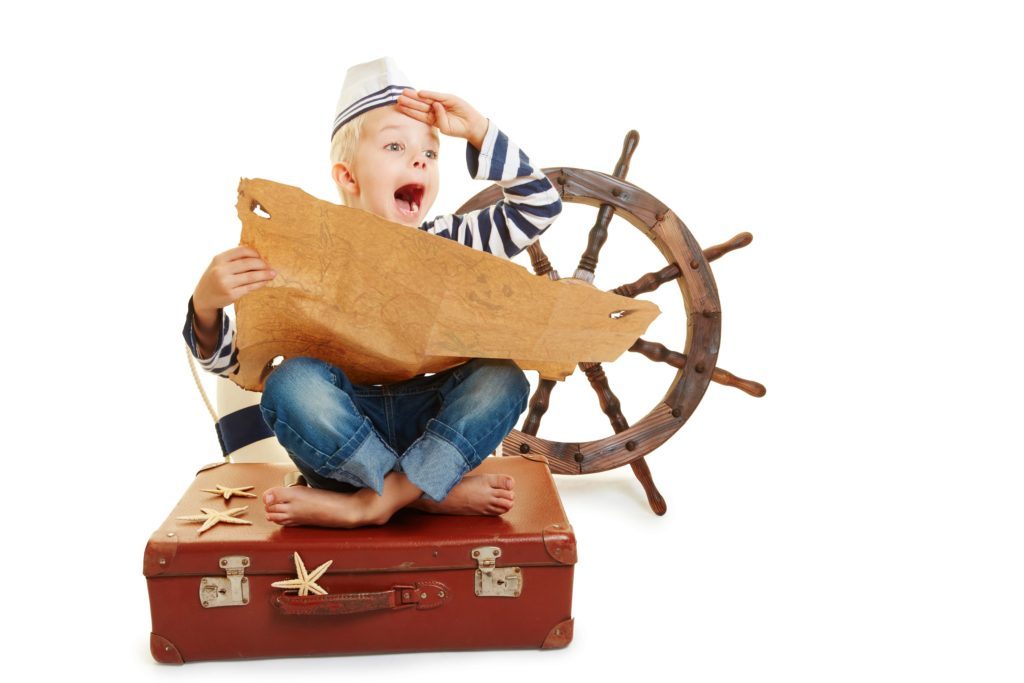 kid sitting on a suitcase with a pirate map and pirate wheel playing a game