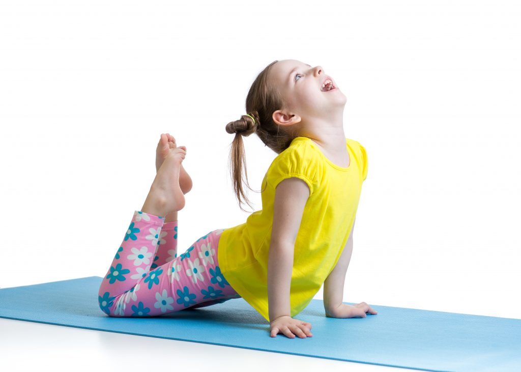 girl doing a modified swan or king cobra pose on yoga mat in class