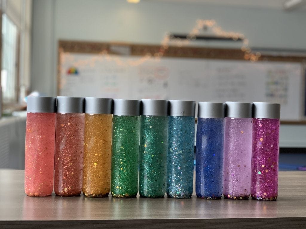 rainbow of glitter calming mindfulness jars lined up in a row, mindfulness craft for kids