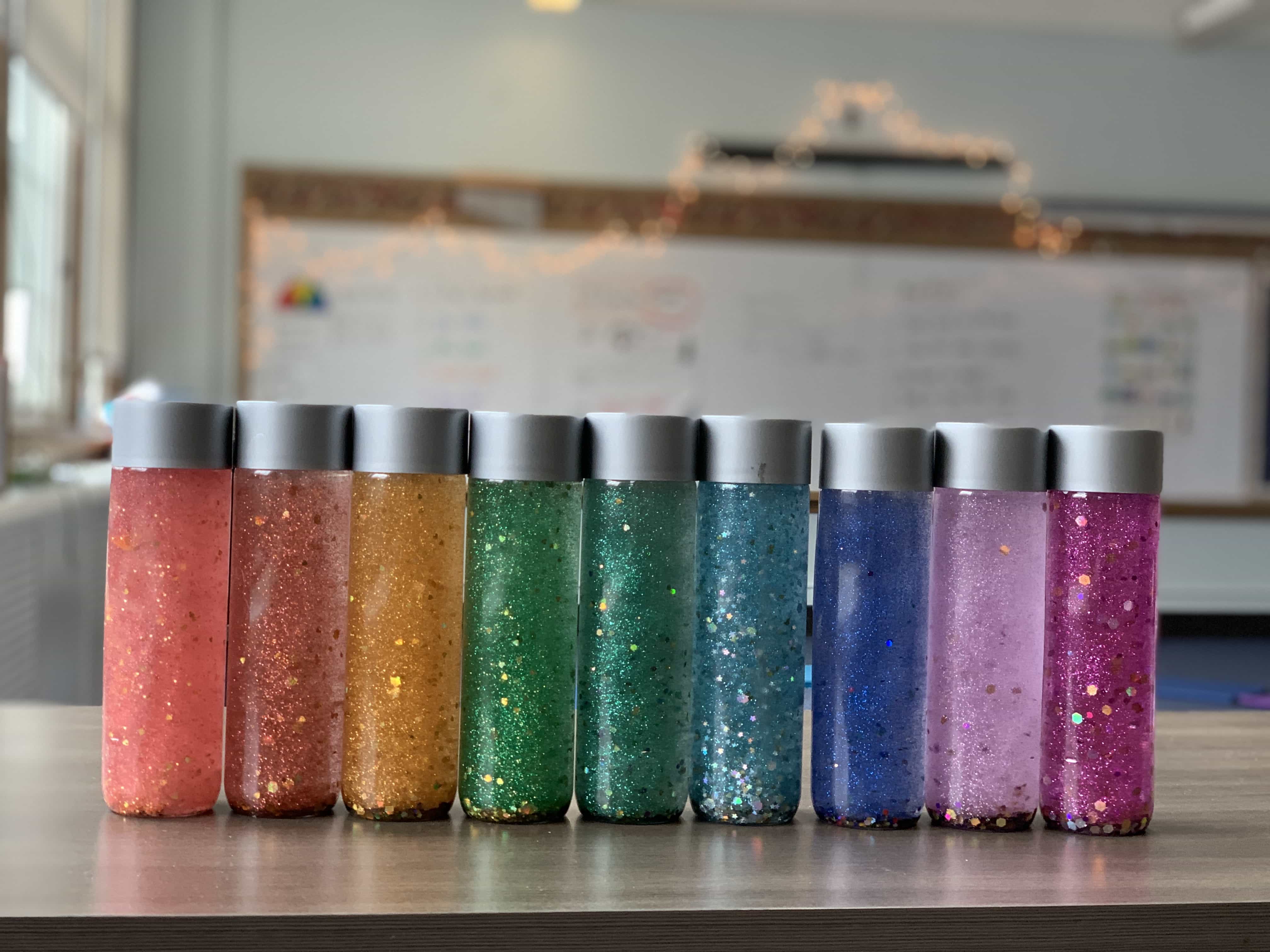 rainbow of glitter calming mindfulness jars lined up in a row