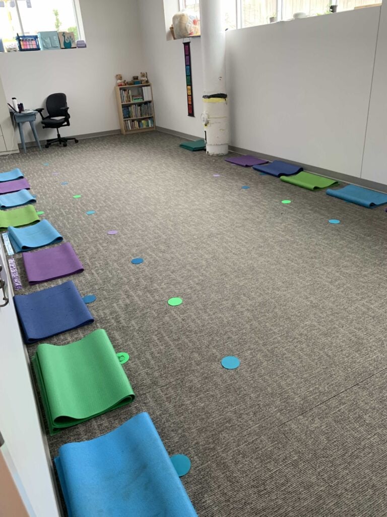 colorful yogo mats and vinyl dots on the carpeted floor for kids yoga class