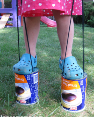 little girl balanced on coffee can stilts