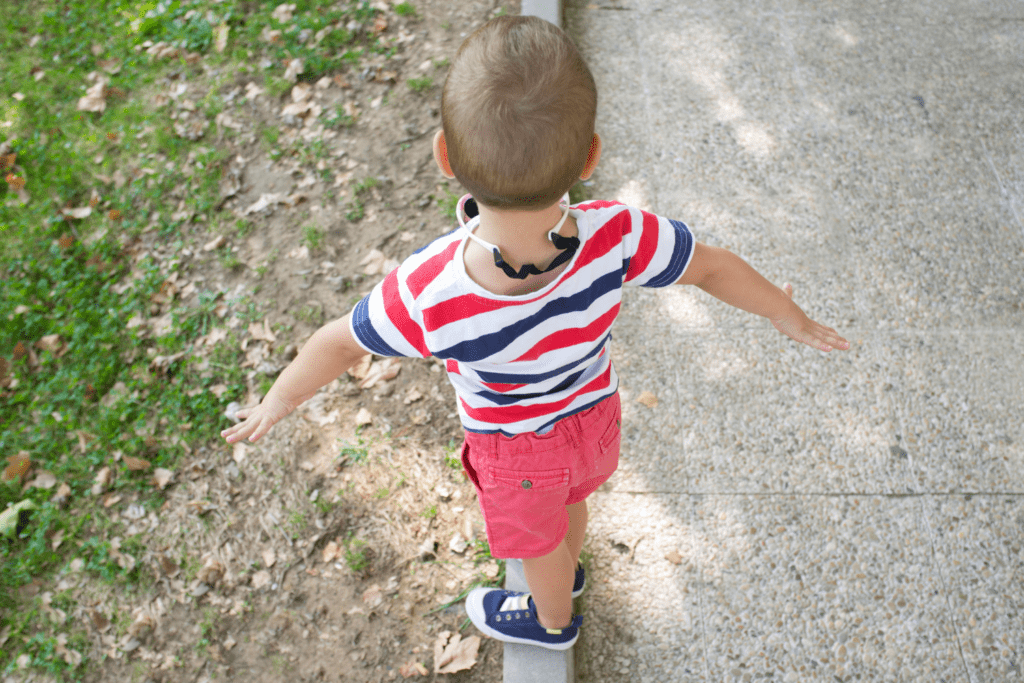 little boy in striped shirt walking on a pretend balance beam for circus-themed yoga