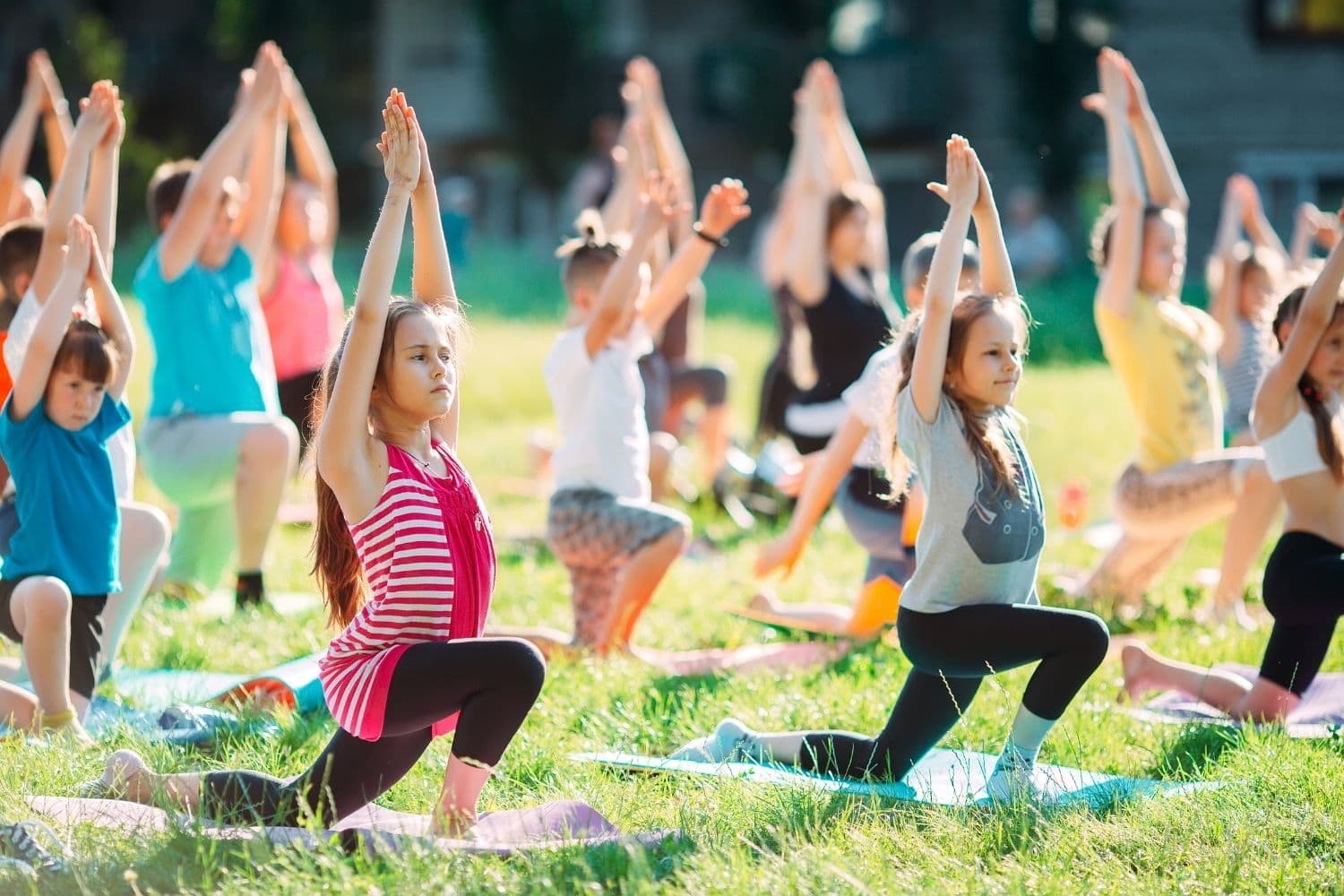 kids practicing a yoga sequence in a class outside on yoga mats
