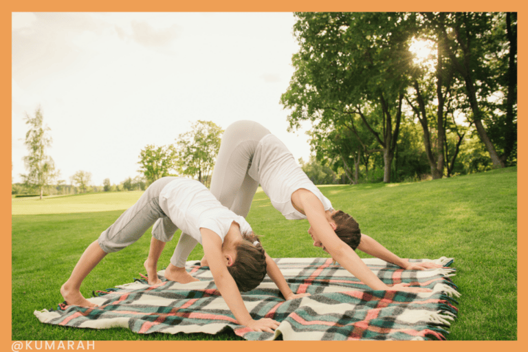 child and parent yoga outside on blanket doing down dog pose