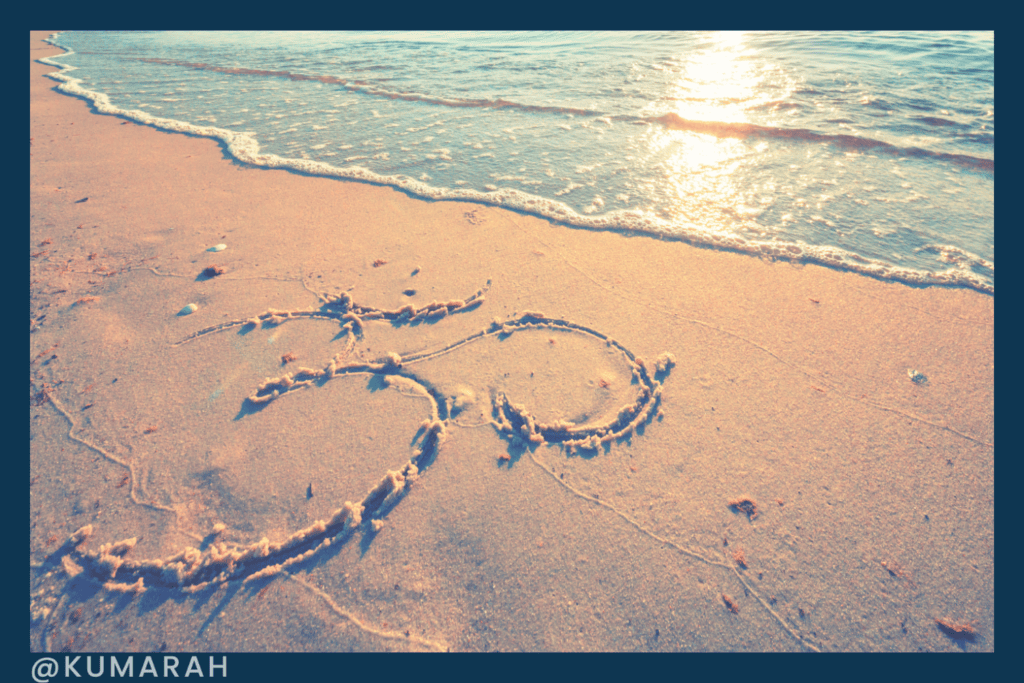 OM symbol on a beach with the ocean