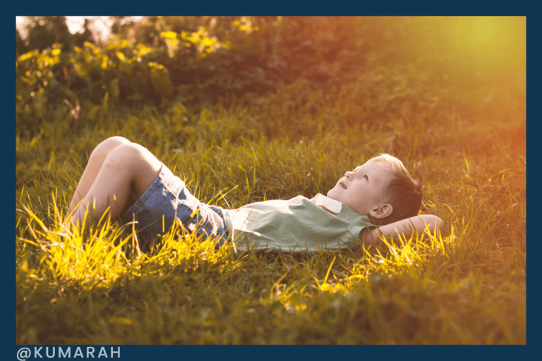 child laying in grass meditating
