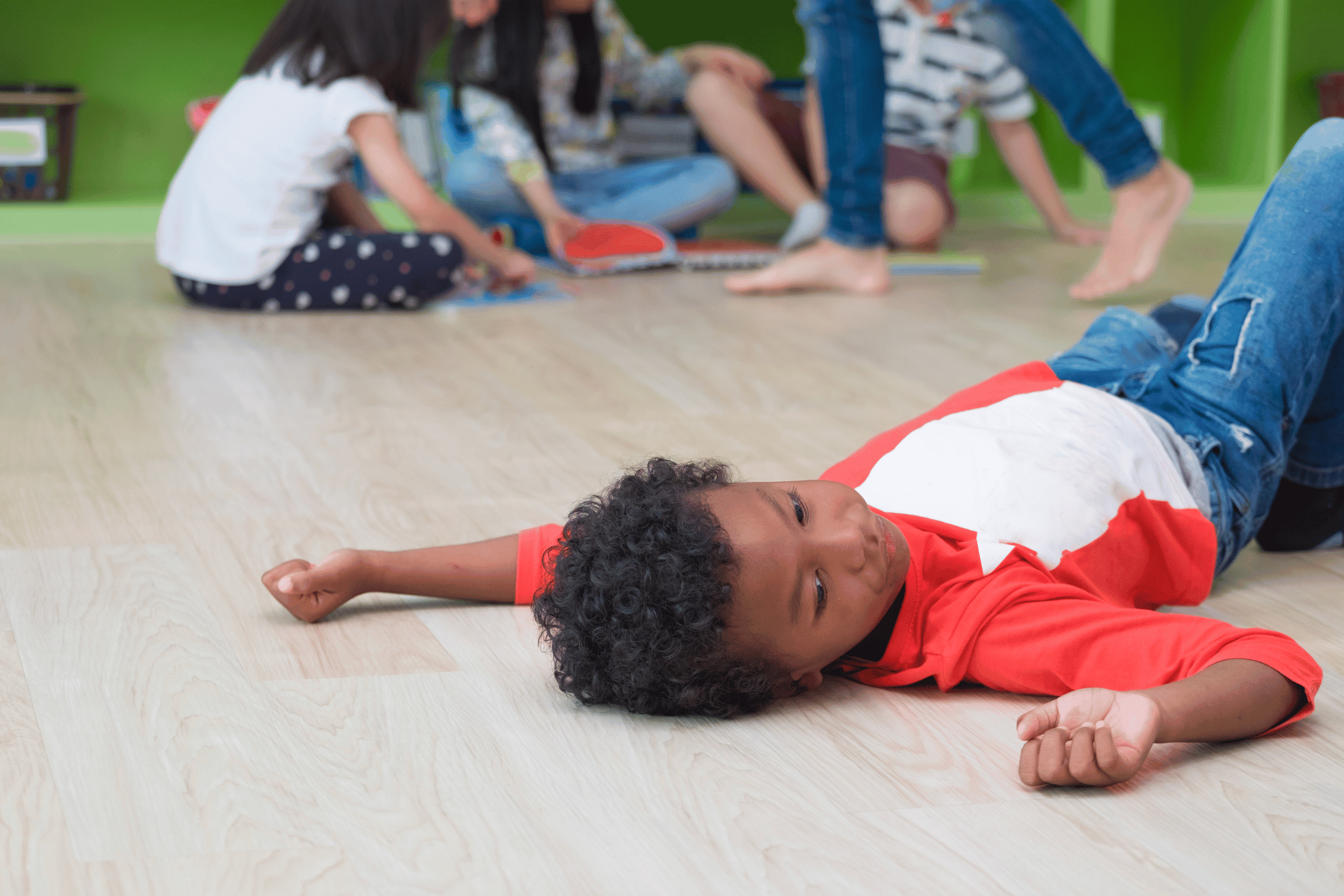 upset boy laying on floor in classroom